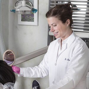 a woman in a white lab coat holding a hair dryer.