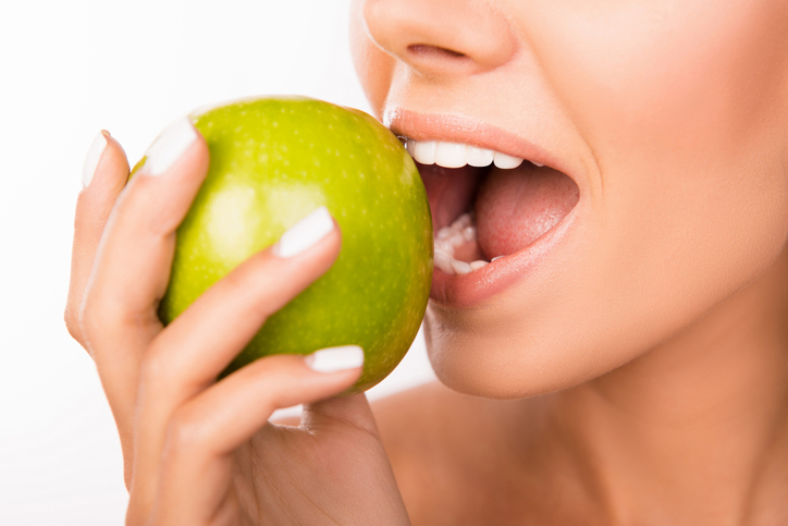a woman biting into an apple with her mouth open.
