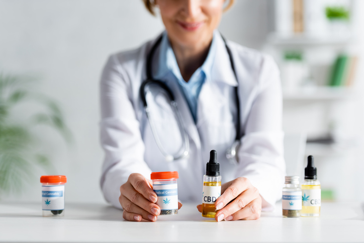 a woman in a white coat is holding three bottles of medicine.