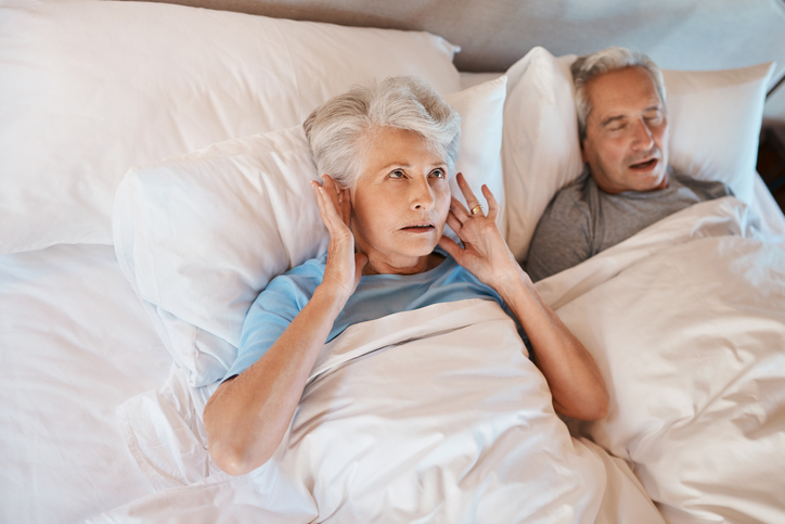 a man and woman laying in bed with white sheets.