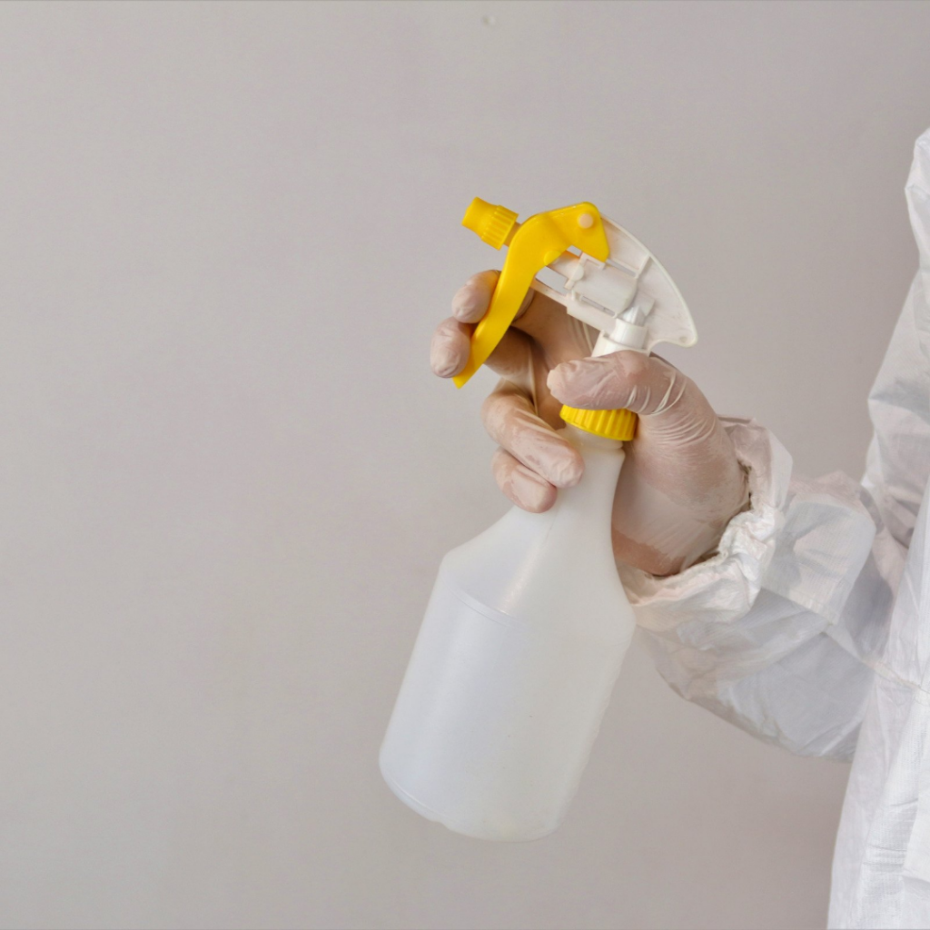 a person in a white suit is holding a plastic bottle with a yellow handle.