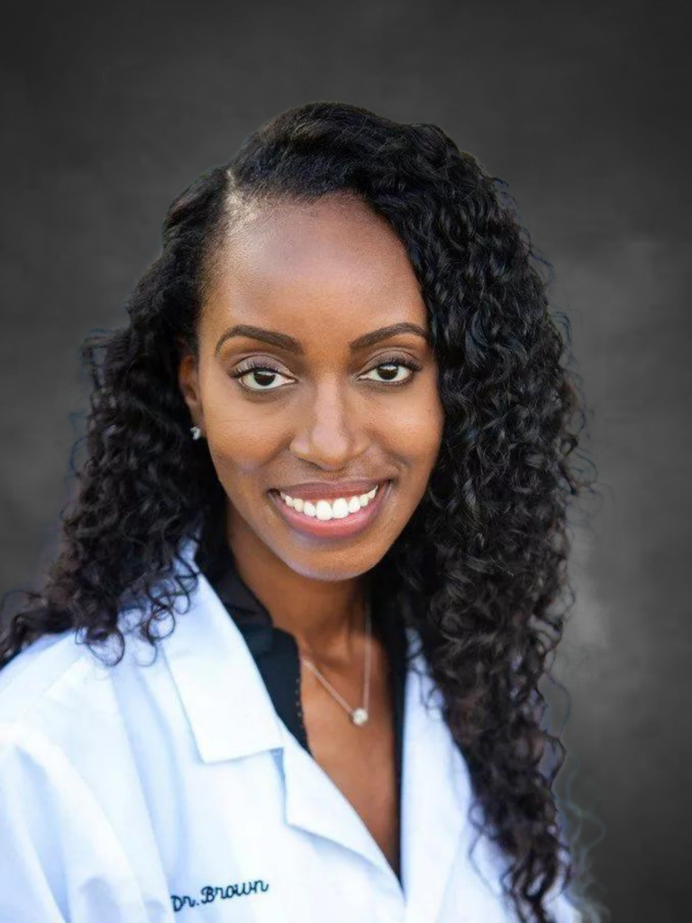 a woman in a white lab coat smiling.